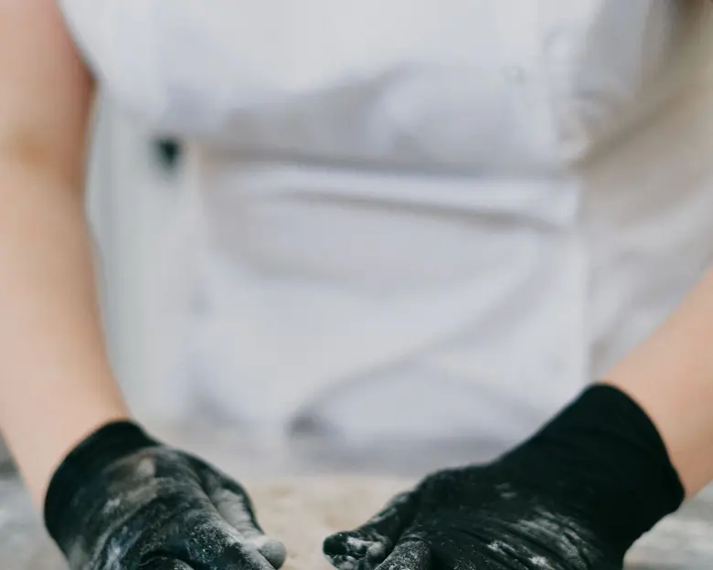 Mani di un pasticcere che lavorano un impasto sul piano infarinato del laboratorio