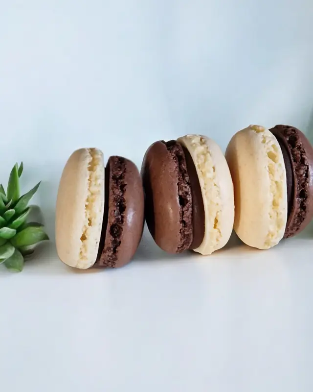 Quattro macaron chiari e scuri allineati in fila su fondo azzurro tenue