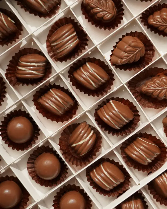 Scatola di praline di cioccolato disposte in file regolari dentro i pirottini